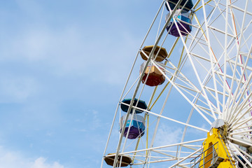 Ferris wheel in amusement Park with clouds and blue sky background.