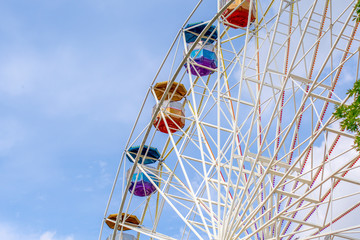 Ferris wheel in amusement Park with clouds and blue sky background.