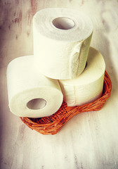 Three rolls of soft white toilet paper on a wicker basket