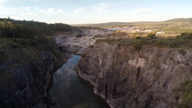 Fly over reveals a quarry and swiftly flowing river cutting the land in two