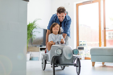 Father helping his son to drive a toy peddle car