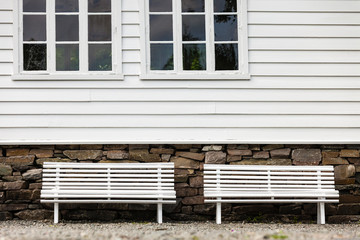 Symmetrical two white bench in front traditional house.