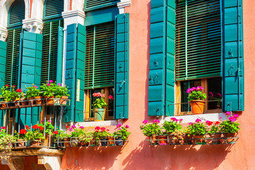 Fototapeta na wymiar Windows with green shutters and flowers in Venice, Italy.