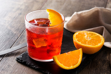 Negroni cocktail with piece of orange in glass on wooden table