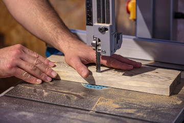 detail of a carpenter's hand next to a band saw blade.