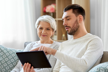 family, generation and technology concept - happy smiling senior mother and adult son with tablet...