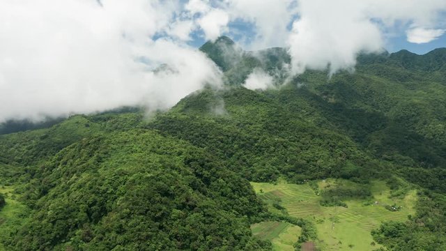 Aerial drone view of clouds moving across the slopes of Mount Hibok-Hibok volcano with lush green farmland below (Camiguin, Philippines)