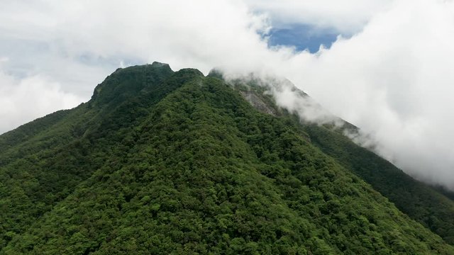 Aerial drone view of clouds moving over the slopes of the volcano Mount Mambajo on Camiguin island