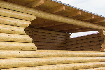 Gazebo made of logs. Window in wooden terrace. Elements of wooden construction.