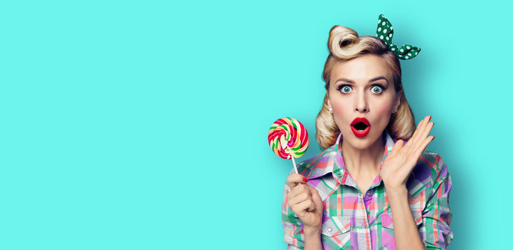 Photo of beautiful very surprised woman with lollipop, in pinup style, over blue green color background