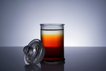 A jar with golden liquid on white background
