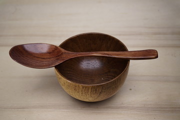 a wooden bowl and a wooden spoon or spatula on wooden background