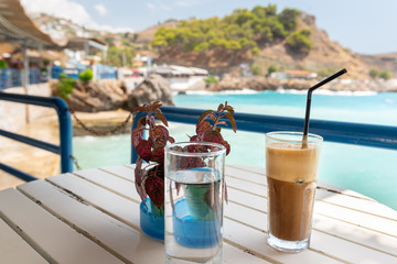 Fototapeta na wymiar Glasses with Ice coffee (frappe) and water on wooden table and blue sea on a background