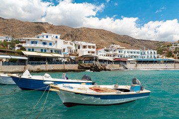 Fototapeta na wymiar Small moored fishing boats in blue lagoon of Crete island.