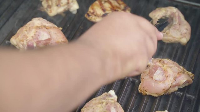 Flipping chicken breasts on a barbecue revealing grill marks