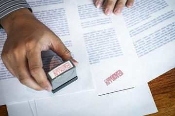 Hands of businessman stamp on paper document to approve business investment contract agreement