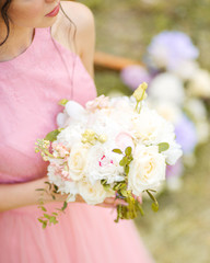 Modern bouquet of different flowers and green leaf. Beautiful wedding bouquet in bride's hands. 