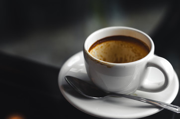 close up modern hot black coffee the espresso on dark background with coffee bubble foam pattern and texture in empty white cup looking and feel so delicious on glasses table in coffee shop.