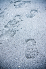 Heavy footprint left on a muddy sand by a male boot.