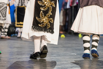 Close up of legs of young Romanian dancers perform a folk dance in traditional folkloric costume....