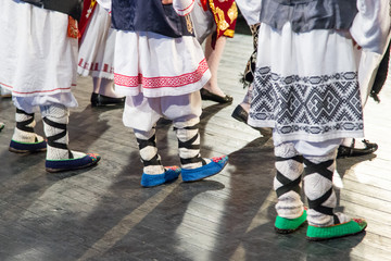 Close up of legs of young Romanian dancers perform a folk dance in traditional folkloric costume....