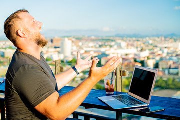 man indignant working on a computer in a cafe with a beautiful view