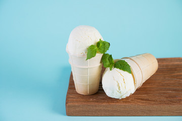 Vanilla, cream ice cream in a waffle Cup on a blue background. Copy space. Horizontal photo.