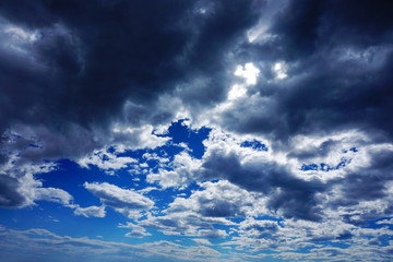 Dramatic sky with many rain clouds which cover a blue sky