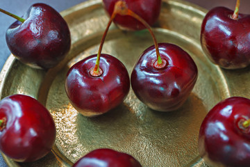 Lots of ripe juicy cherries on a Golden platter. Close-up view from above. Raw materials for natural juice, fresh fruit drink or compote