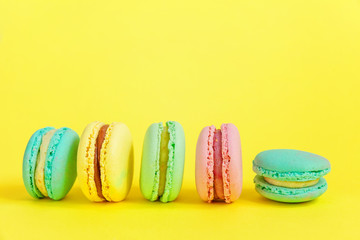 Sweet almond colorful unicorn pink blue yellow green macaron or macaroon dessert cake isolated on trendy yellow modern fashion background. French sweet cookie. Minimal food bakery concept. Copy space