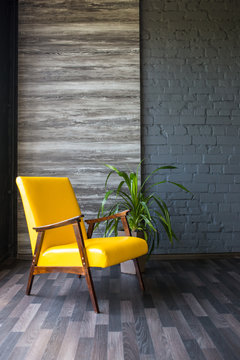 Stylish retro yellow chair in the gray room. Brick gray wall. Room.