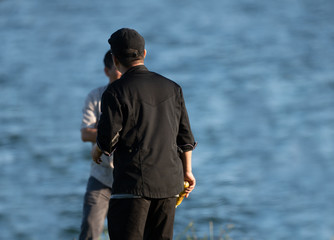 unknown fisherman is having a conversation with an associate while holding corn at a cookout on a sunny day at the park