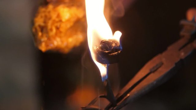 Riveting rose iron in flame kept at fire in a traditional blacksmith workshop 