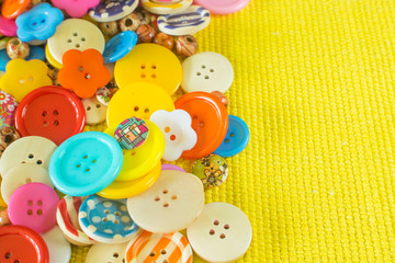 Various sewing buttons on yellow background with place for text