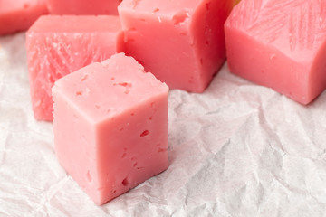 Pink cheese cubes for a snack. Close up. Copy space