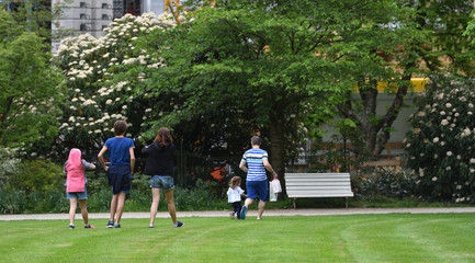 The family walks on the cropped grass in a city park in a European city. Mom, Dad and 3 daughters on a walk in the park