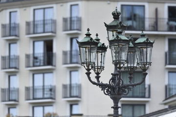 Fototapeta na wymiar Beautiful classic iron lamppost of six lamps with diode bulbs on the background of a building with windows in a European city