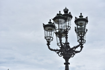 Fototapeta na wymiar Beautiful classic iron lamppost of six lamps with diode bulbs against a cloudy sky in a European city