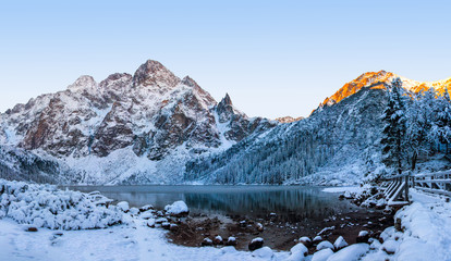 Winter mountains. Snowy mountain on Morskie Oko icy lake. Winter rocks on clear morning