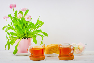 two cups of black tea, marshmallows, cake slices and a pink flower pot on the table, with copy space