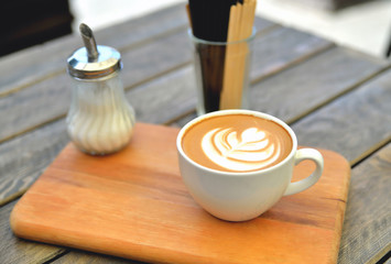 cup of coffee on a wooden stand is on the table in a cafe summer morning