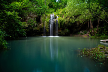 Waterfall and a beautiful lagoon lake for relaxing in the summer forest.