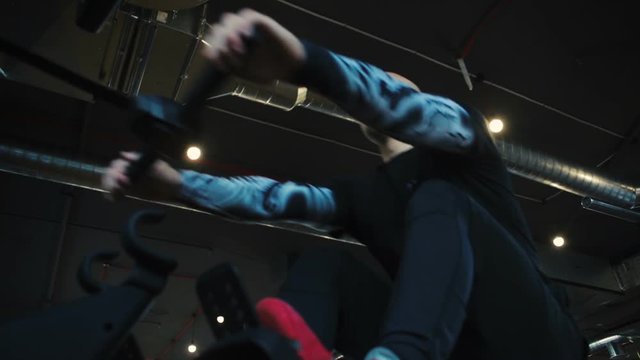 bald emotional guy exercises on seated cable row machine in modern gym close low angle shot slow motion