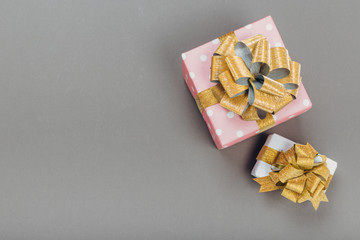 beautiful gift box wrapped in paper with a gold ribbon and a bow on a gray surface. Top view