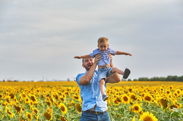 Cheerful father and little son on a walk in the field. Parent throws son . Father's day.