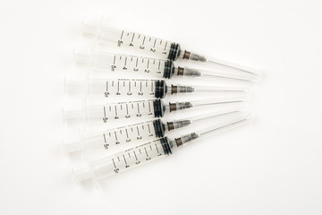 Many used plastic syringes with needles on a white background, top view