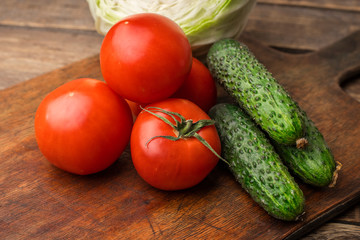Tomatoes and fresh cucumbers on a wooden cutting board. Fresh harvest