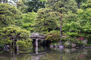 Fototapeta na wymiar Beautiful scenery at the Kyoto Imperial Palace. View of the Oikeniwa gardens, with a pond and bridges. On a rainy day, droplets are visible in the air.