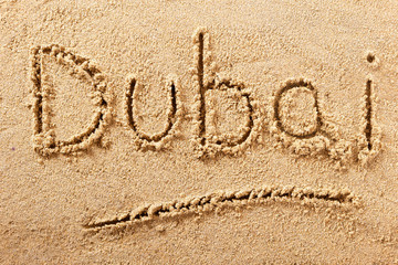 Dubai word written in sand on a sunny summer beach holiday vacation travel destination sign writing message photo