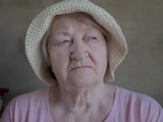 Elderly woman with bouquet of medical daisies in pink T-shirt and hat. Pensioner engaged in...